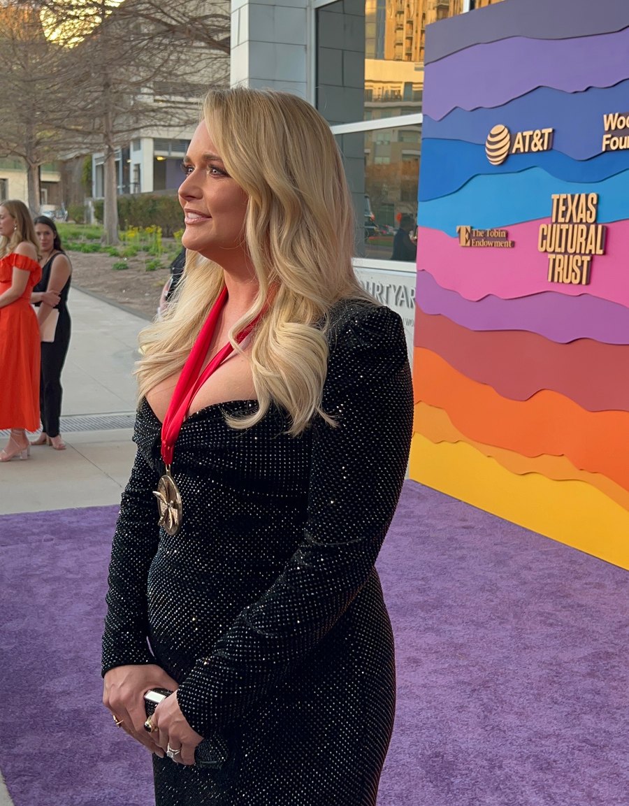 Miranda Lambert wearing the Texas Medal of Arts on a red ribbon, on the purple carpet.